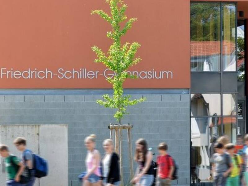 Fassade des D-Baus des Friedrich-Schiller-Gymnasiums mit Schriftzug und Schülern im Vordergrund